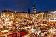 Weihnachtsmarkt bei Nacht mit bunten Ständen und Lichtern in einer Stadt.