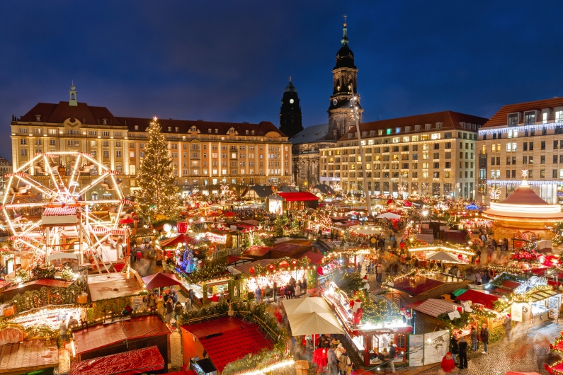 Weihnachtsmarkt bei Nacht mit bunten Ständen und Lichtern in einer Stadt.