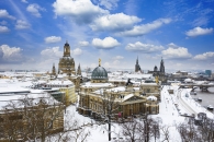 Winterliches Dresden mit der verschneiten Frauenkirche und der Elbe im Hintergrund.