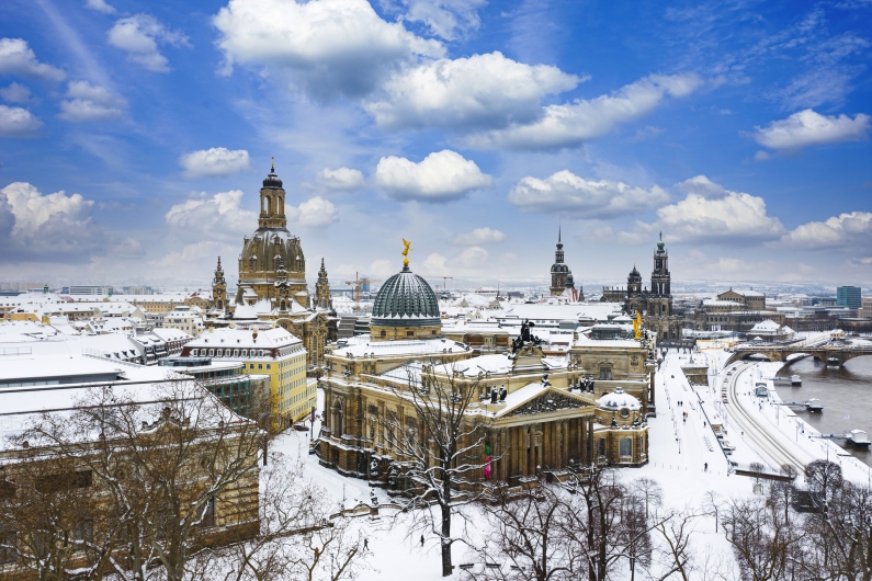 Winterliches Dresden mit der verschneiten Frauenkirche und der Elbe im Hintergrund.