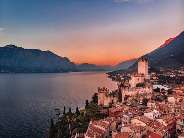 Luftaufnahme von Malcesine am Gardasee bei Sonnenuntergang mit Burg und Bergen.