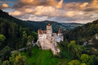 Schloss in einer bewaldeten Landschaft bei Sonnenuntergang.