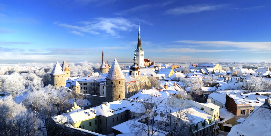 Verschneite Altstadt mit Türmen und Kirche unter blauem Himmel.