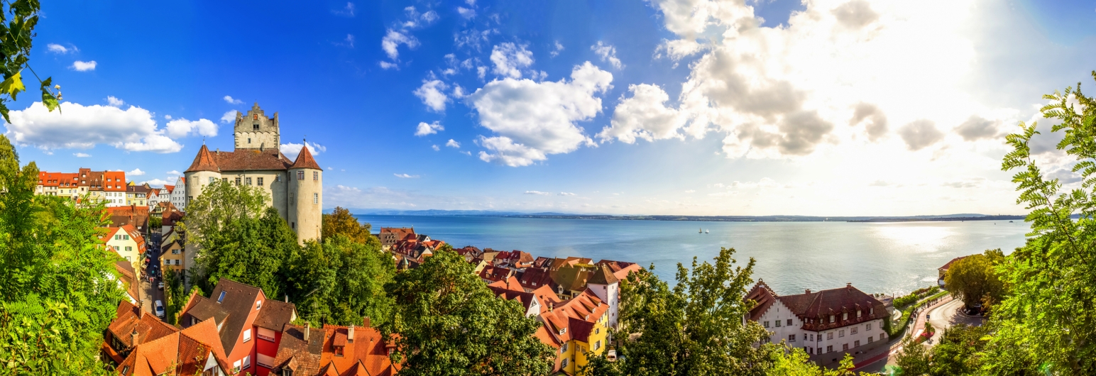 Mittelalterliche Burg und See unter blauem Himmel mit Wolken.