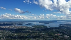 Luftaufnahme einer Stadtlandschaft mit Meer und bewölktem Himmel.