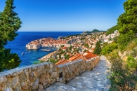 Blick auf die Altstadt von Dubrovnik mit Küste und blauem Meer im Hintergrund.