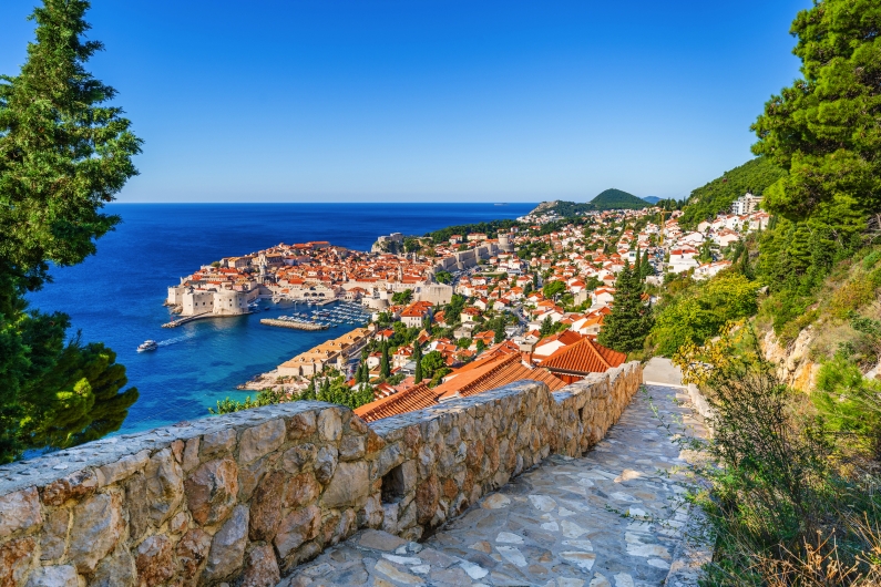 Blick auf die Altstadt von Dubrovnik mit Küste und blauem Meer im Hintergrund.