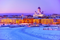 Verschneite Winterlandschaft mit beleuchteter Stadt und Dom im Hintergrund.