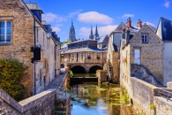 Fluss fließt zwischen alten Steinhäusern in einer historischen Stadt.