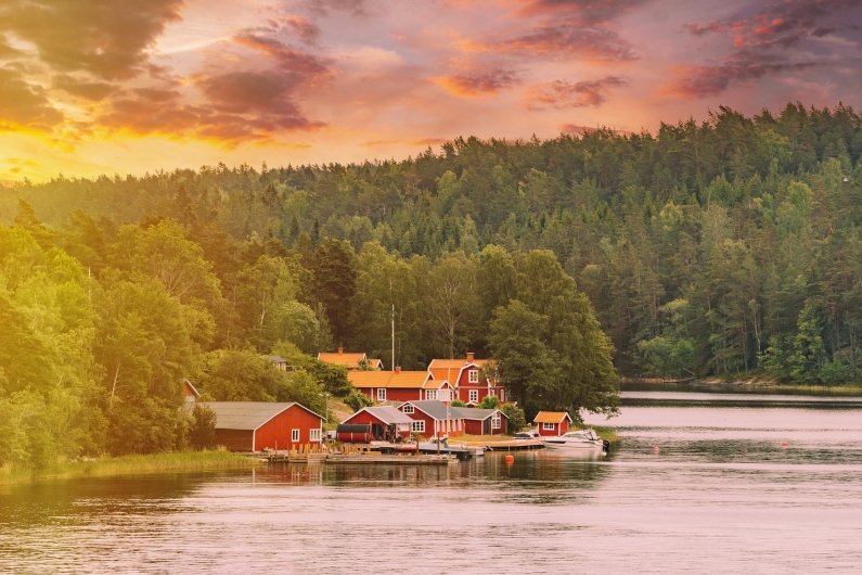 Häuser am Seeufer im Wald bei Sonnenuntergang.
