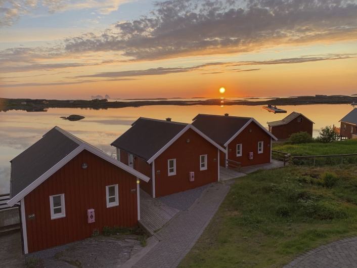 Rote kleine Holzhäuser am Meer unter roter Sonne
