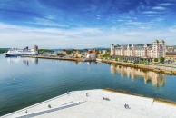 Panorama von Oslo mit historischen Gebäuden, Hafen, Kreuzfahrtschiff, Promenade mit spazierenden Menschen und dem blauen Himmel