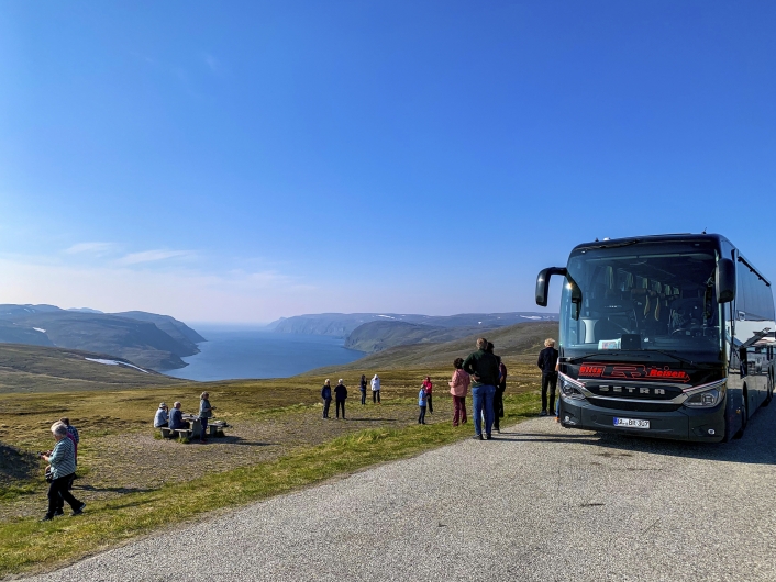 Bus mit Gästen vor Fjordlandschaft