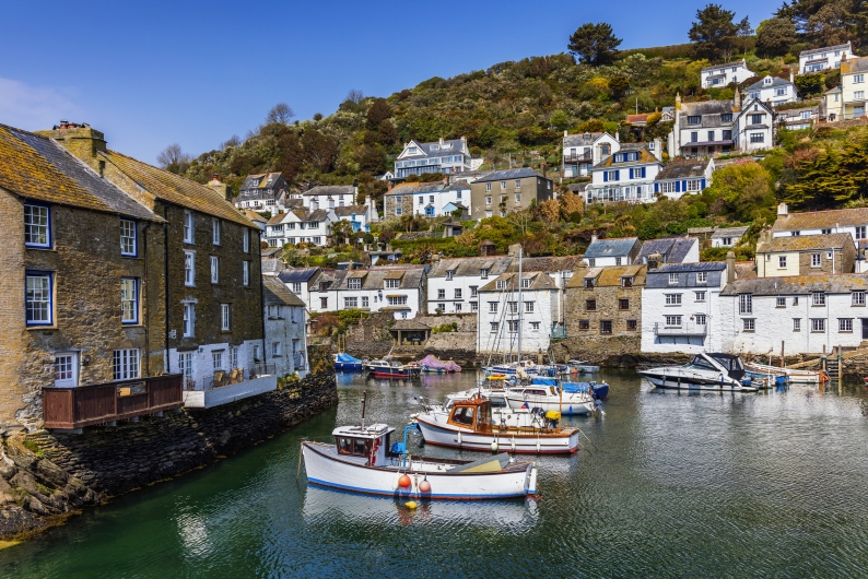 Küstenort mit Booten und Häusern am Hang, sonniger Tag.