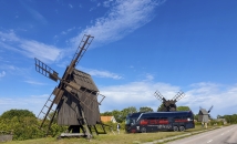 Bus steht vor Holzwindmühlen bei blauem Himmel