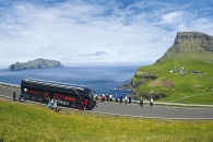 Bus steht an der grünen Küste und Menschen betrachten die Aussicht