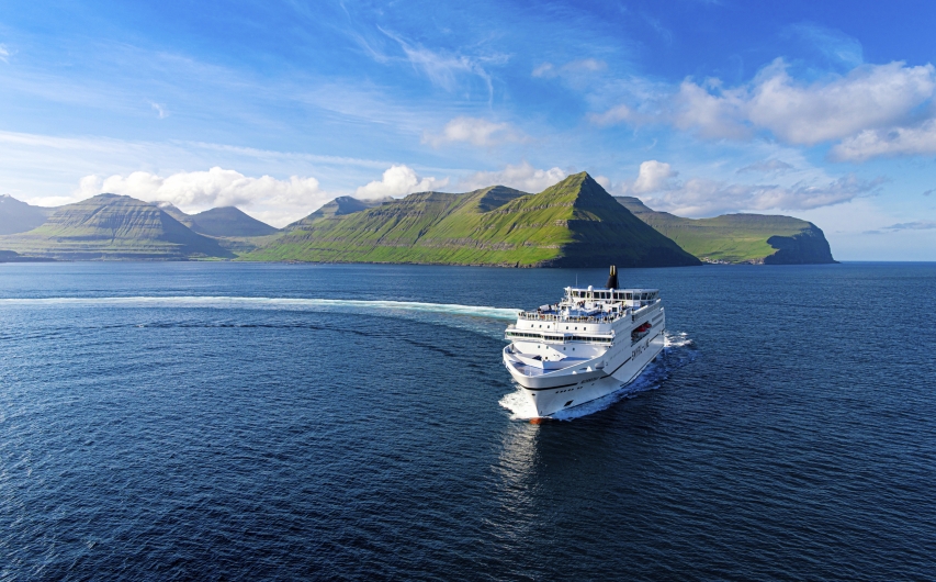 Schiff auf Meer vor grüner Insel