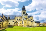 Historisches Kloster mit Turm und grünem Rasen im Vordergrund.