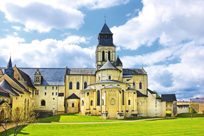 Historisches Kloster mit Turm und grünem Rasen im Vordergrund.