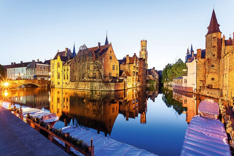 Historische Gebäude am Wasser bei Dämmerung in Brügge, Belgien.