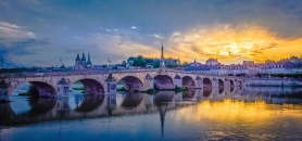 Steinbrücke über einen Fluss bei Sonnenuntergang mit reflektierendem Wasser