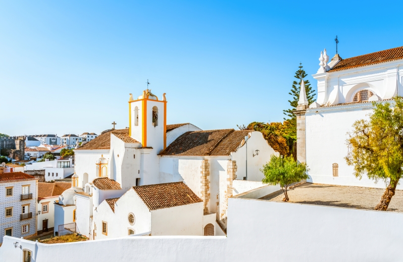 Weiße Kirche und Gebäude unter blauem Himmel.