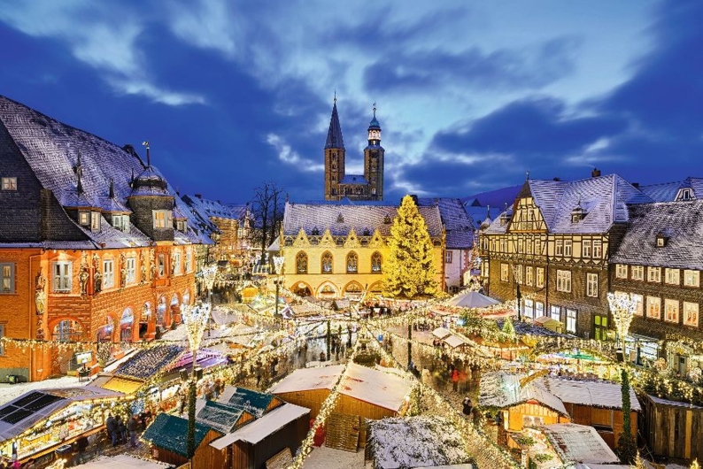 Verschneiter Weihnachtsmarkt in einer historischen Altstadt am Abend.