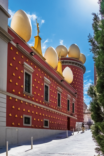 Rotes Gebäude mit großen Eiern auf dem Dach und einem klaren blauen Himmel.