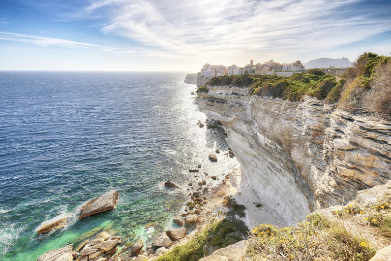 Steile weiße Felsenküste mit Dorf und weites blaues Meer