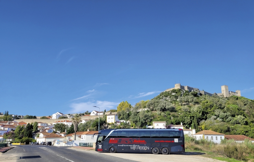 Schwarzer Bus vor einem Ort bei blauem Himmel