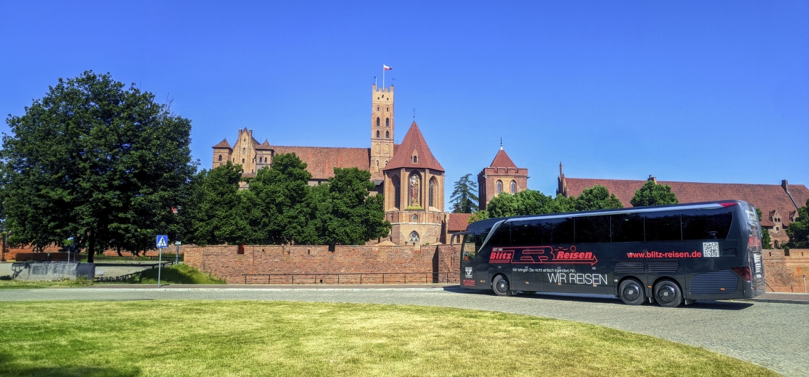 Bus vor orangener Burg