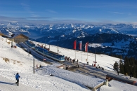 Bahnstation in verschneiter Berglandschaft mit Menschen und Flaggen.