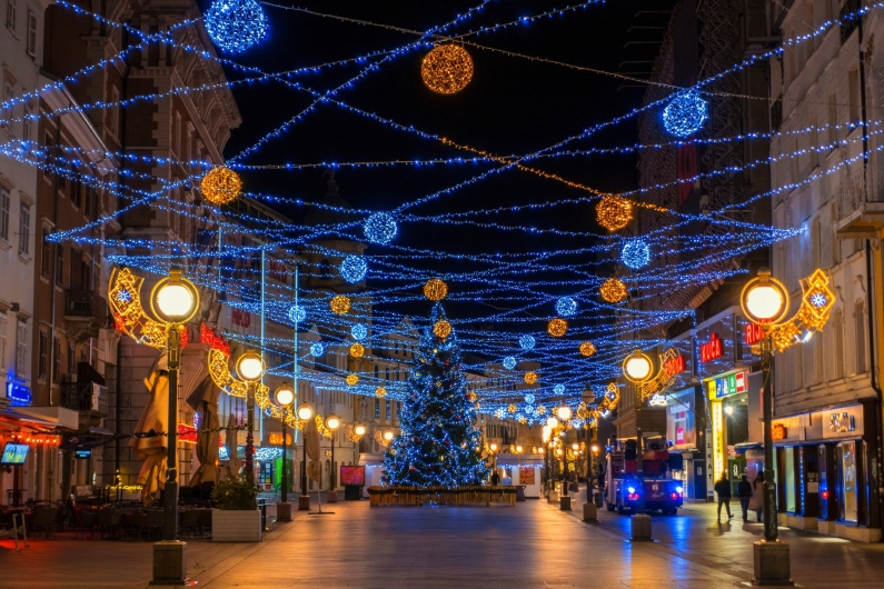 Eine festlich beleuchtete Straße mit Weihnachtsbaum in der Mitte.