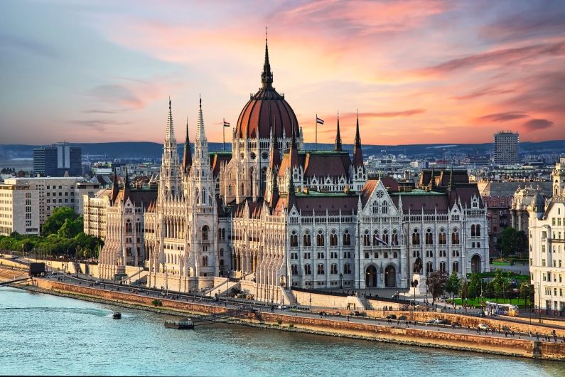 Ungarisches Parlamentsgebäude bei Sonnenuntergang am Donauufer in Budapest.