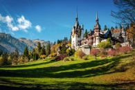 Schloss in alpiner Landschaft bei klarem Himmel und Herbstlaub.