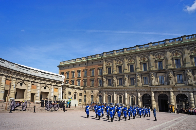 Wachablösung mit Soldaten in blauen Uniformen vor einem historischen Gebäude.