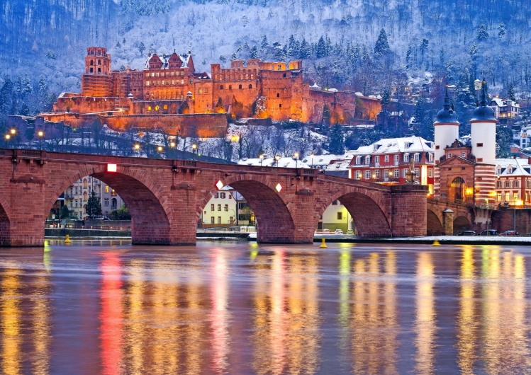Alte Brücke und Schloss Heidelberg im Winter bei Dämmerung reflektieren im Neckar.