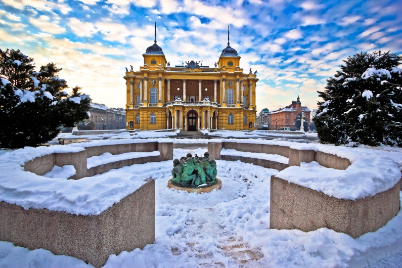 Gelbes Gebäude im Winter, umgeben von Schnee und blauem Himmel.