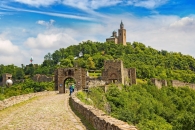 Burg auf einem Hügel mit alten Steinmauern und blauem Himmel im Hintergrund.