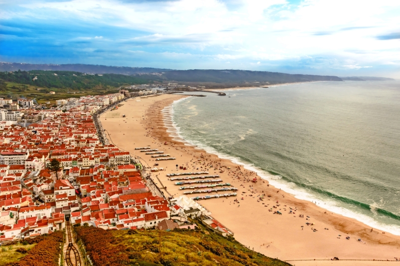 Küstenstadt mit Strand und hoher Klippe am Meer.