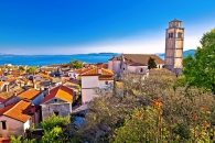 Blick auf pittoreske Küstenstadt mit Kirchturm und Meer im Hintergrund.