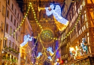 Straßenbeleuchtung mit Engelmotiven vor einer Kathedrale in festlicher Nachtaufnahme