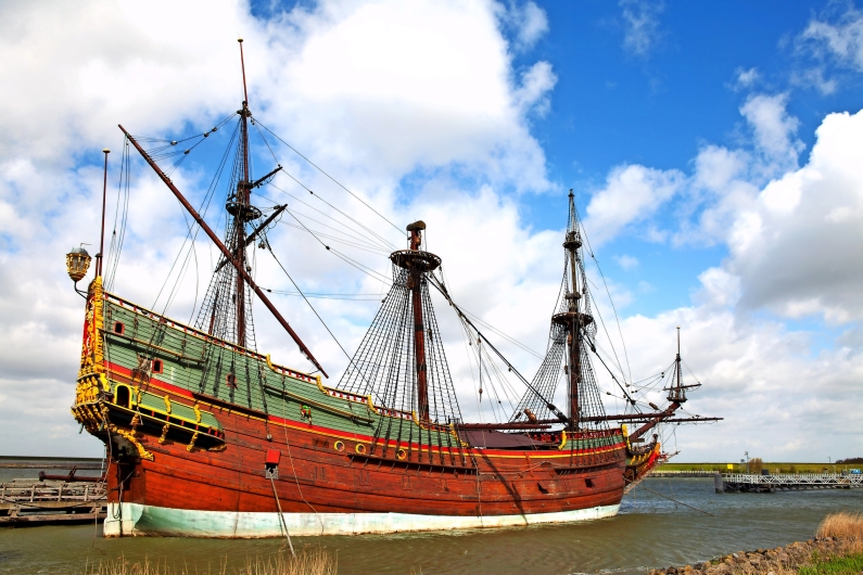 Großes historisches Holzsegelboot im Wasser unter blauem Himmel.
