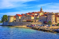 Mittelalterliche Stadt mit Festungsmauern und roten Dächern am Meer.