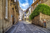 Eine gepflasterte Gasse in einer mediterranen Altstadt mit alten Gebäuden.