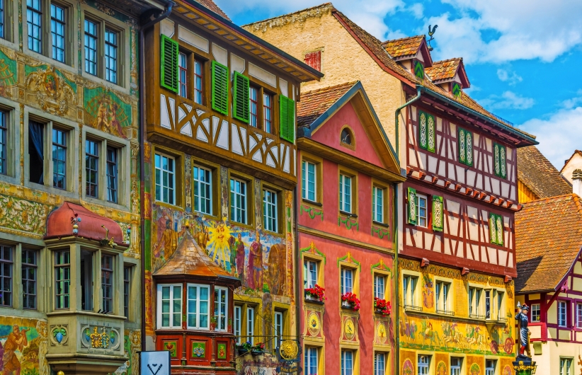 Fachwerkhäuser mit bunten Fassaden und aufwendigen Malereien in einer historischen Altstadt.